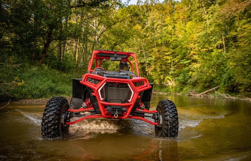 A group of SuperATV employees gathered around a UTV on a sunny day