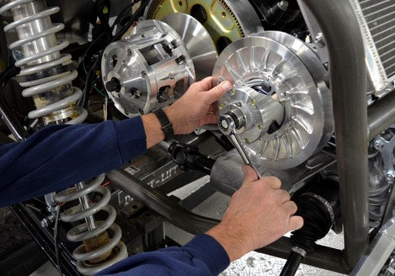 Image of a person using a wrench to work on a UTV