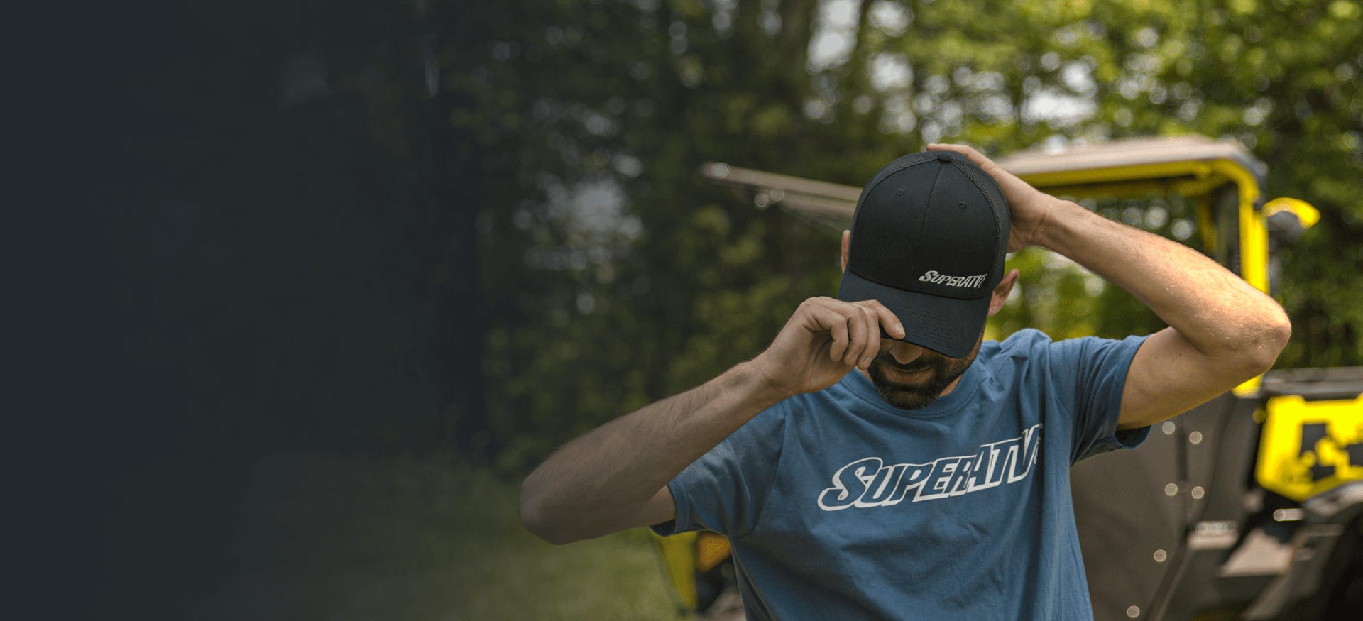 Man with a beard pulling a black SuperATV cap down on his head.