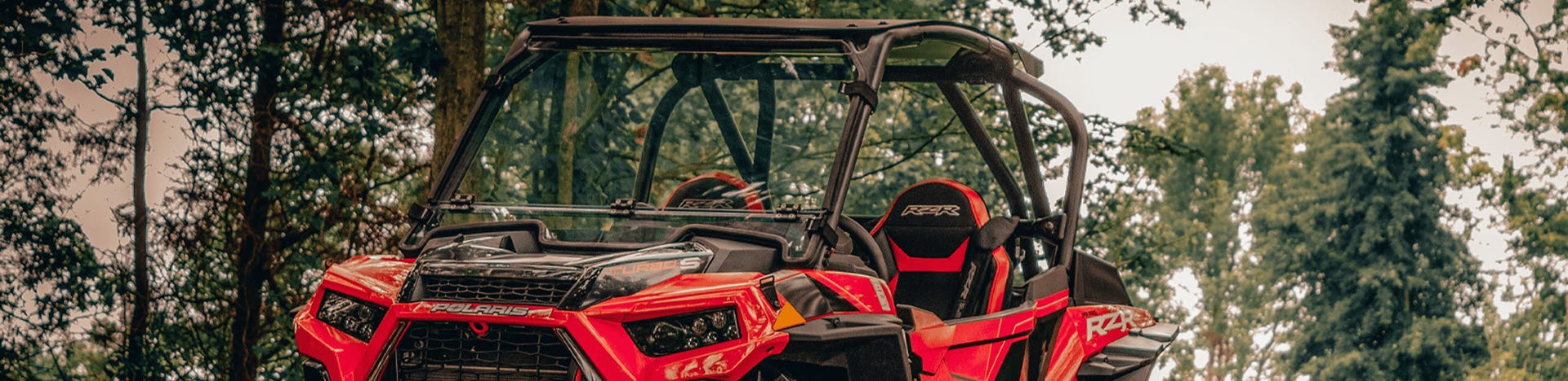 Black and blue Honda Talon with a SuperATV Flip Windshield Installed in a grassy field.